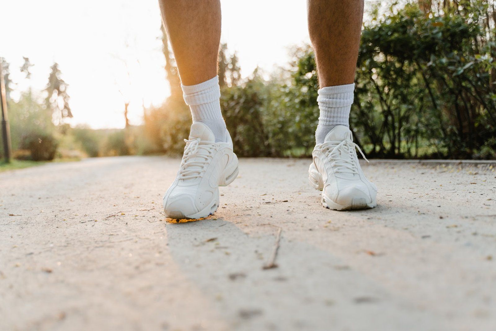 Žmogaus kojos su baltais sportiniais batais lauko take